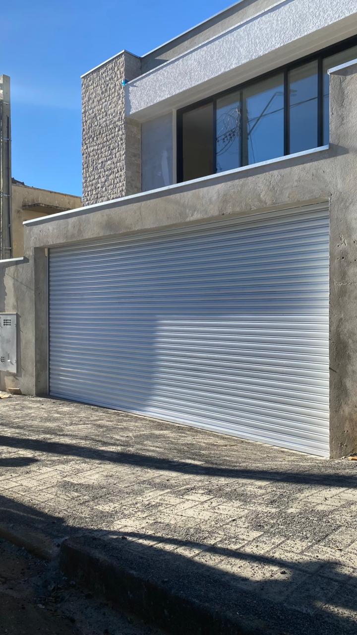 Porta de enrolar branca automatizada instalada em garagem residencial